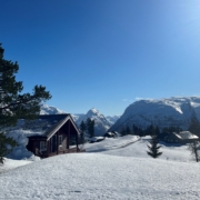 Hytte, blå himmel og snøkledde fjell